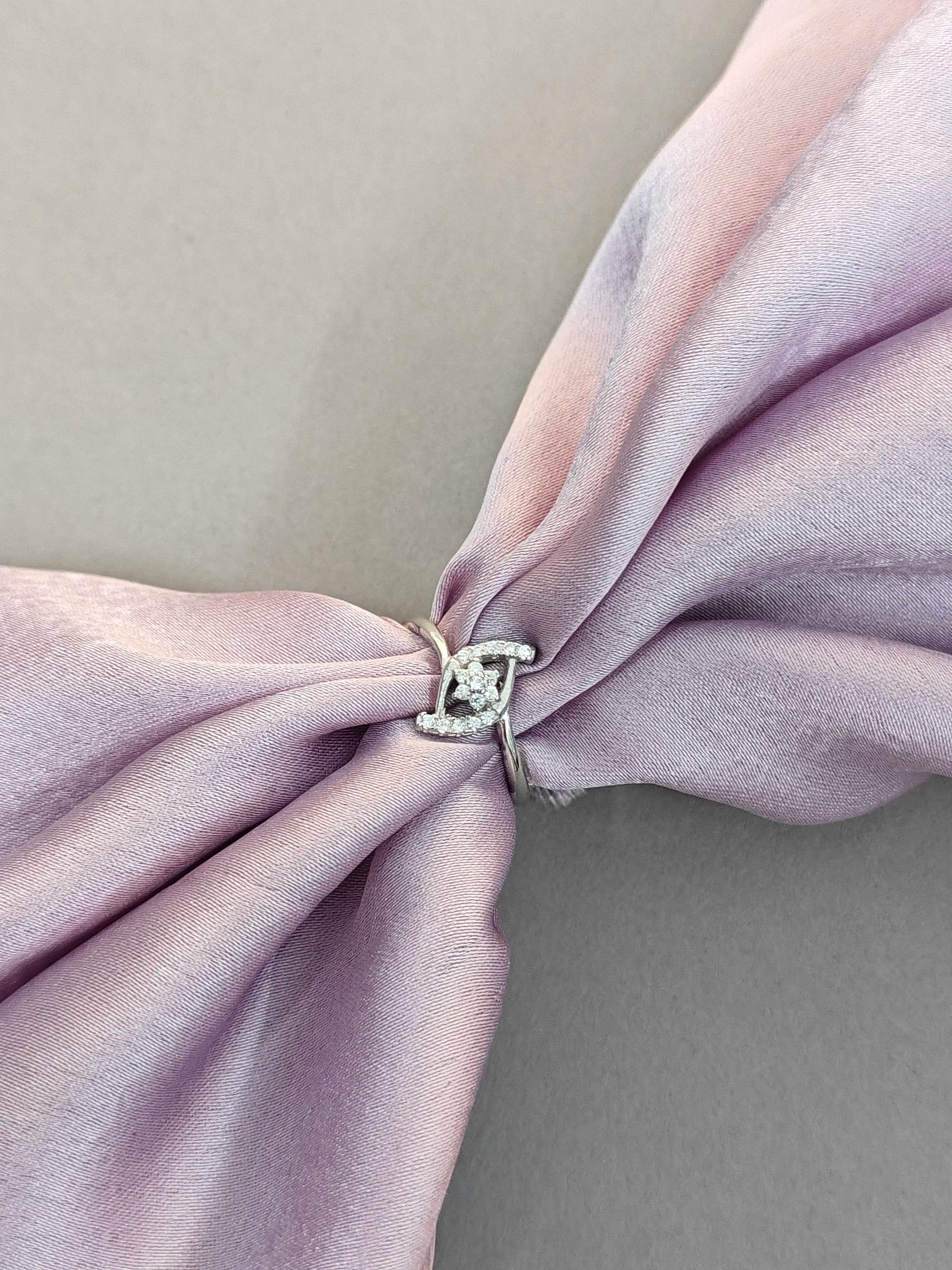 Close-up of a silver ring on a pink fabric bow against a neutral background